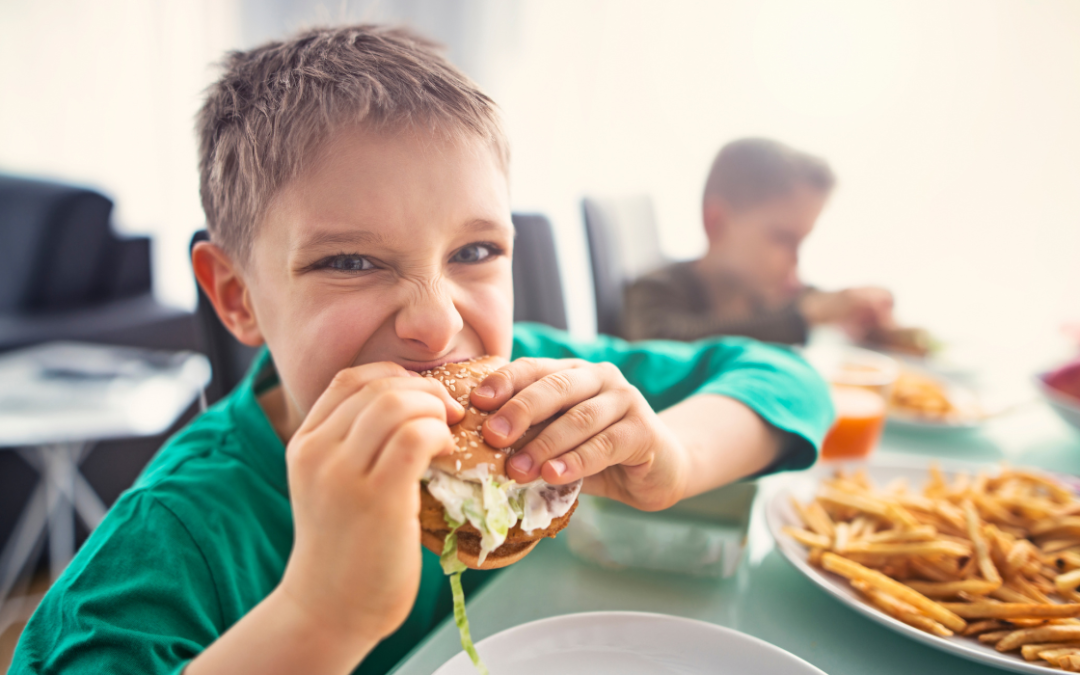 young boy eating burger and fries